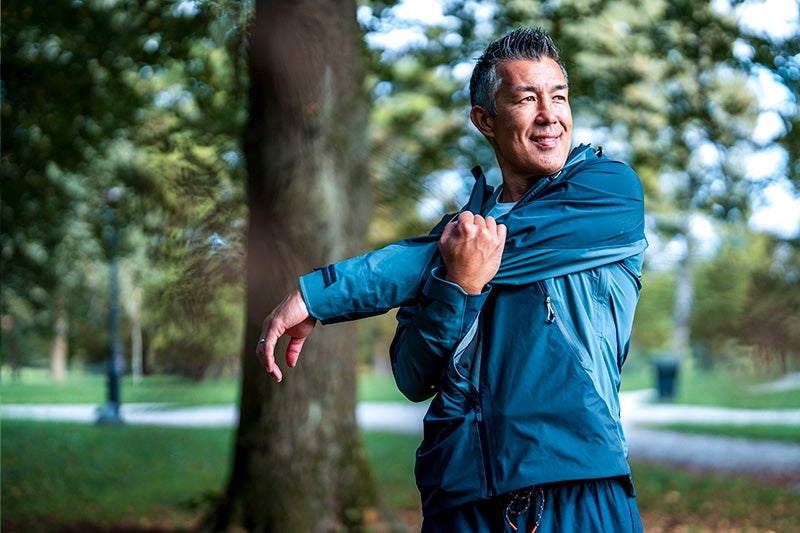 Man in a green track suit stretching after a run.