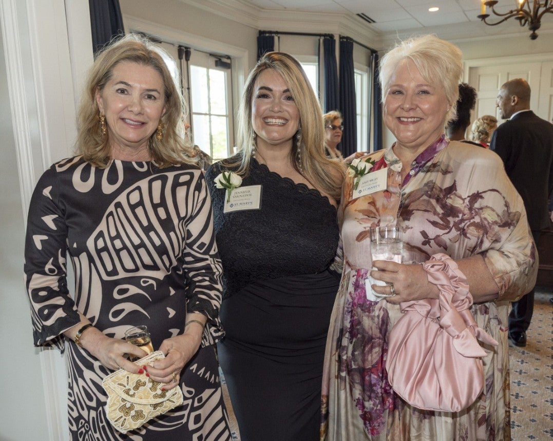 Three women, dressed elegantly smiling at the camera. (Photo Credit: Wingate Downs)