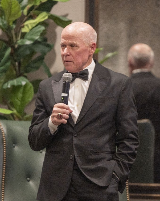 Man in tuxedo talking into a microphone. (Photo Credit: Wingate Downs)