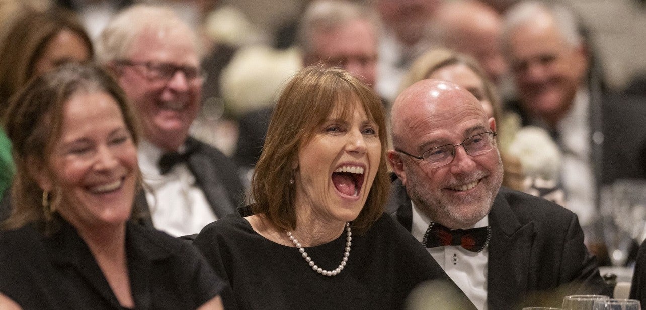 Photo of a woman sitting in the crowd, laughing. (Photo Credit: Wingate Downs)