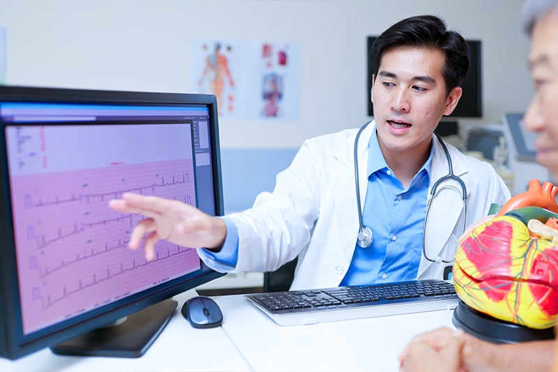 Electrophysiologist explaining test results to a patient while both sit at a computer. 