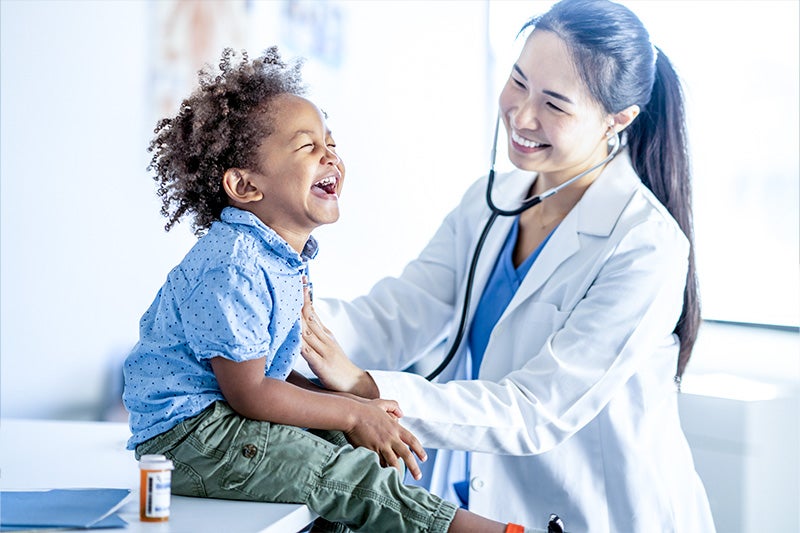 Physician and child laughing while their heartbeat is checked.