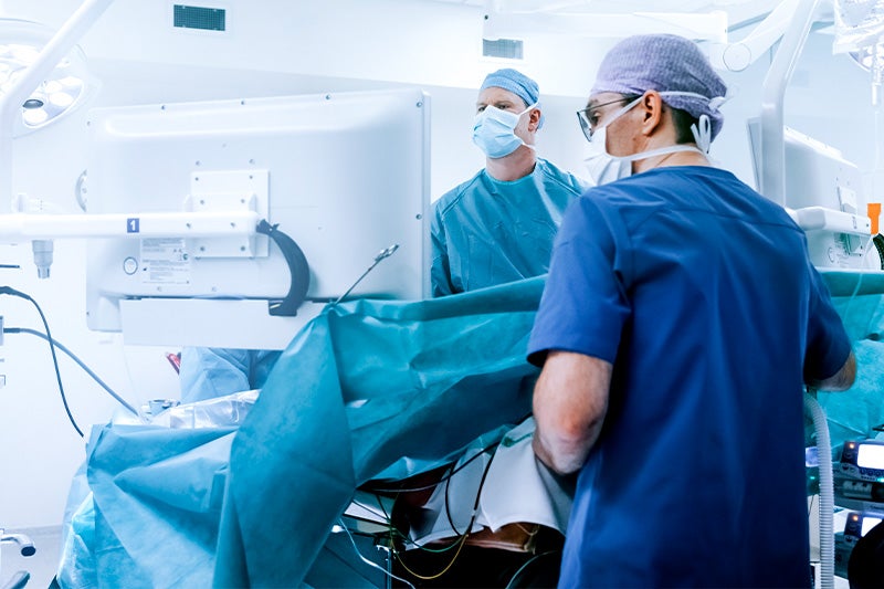 Surgeons in a Operating Room (OR) performing Laparoscopic Surgery on a patient.