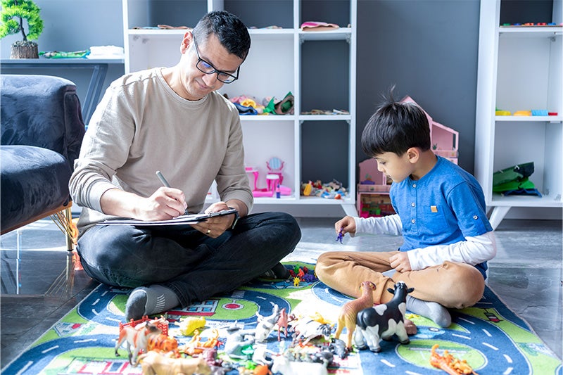Occupational therapist working with young child on the floor.