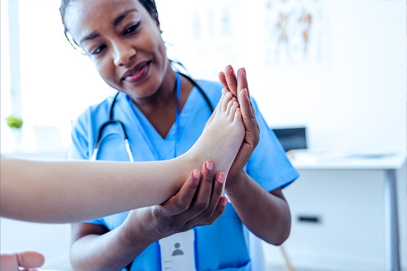 Physician examining arthritis patient's ankle.