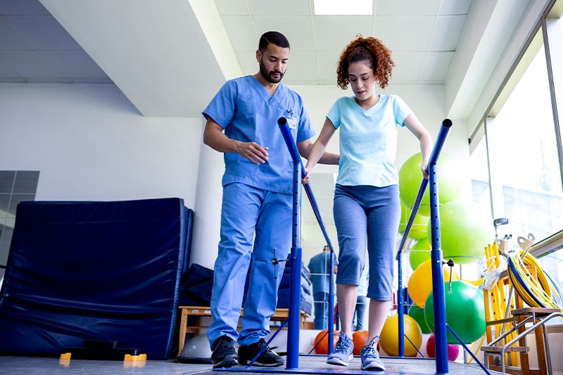 Physical Therapist supporting a patient through a walking exercise.