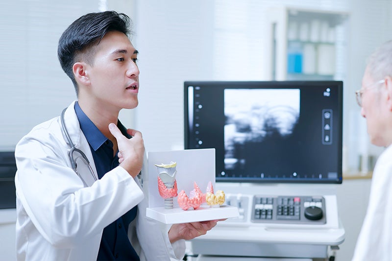 Surgeon explaining how the Thyroid works and is located to a patient.