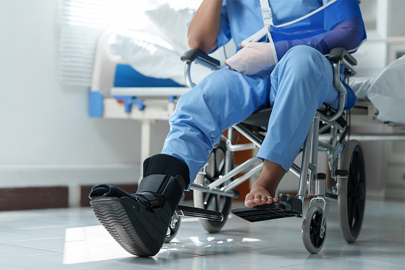 Photograph of a surgery patient in a wheelchair with a protective boot over their foot.