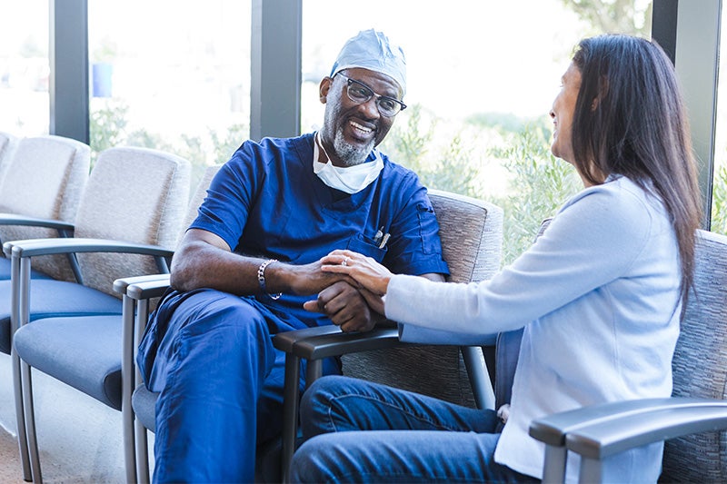 Surgeon clasping hands with a family member of a patient who has finished their surgery.