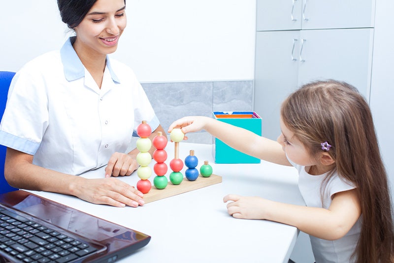 Occupational therapist assisting a child with Developmental Milestone Delay Therapy techniques.