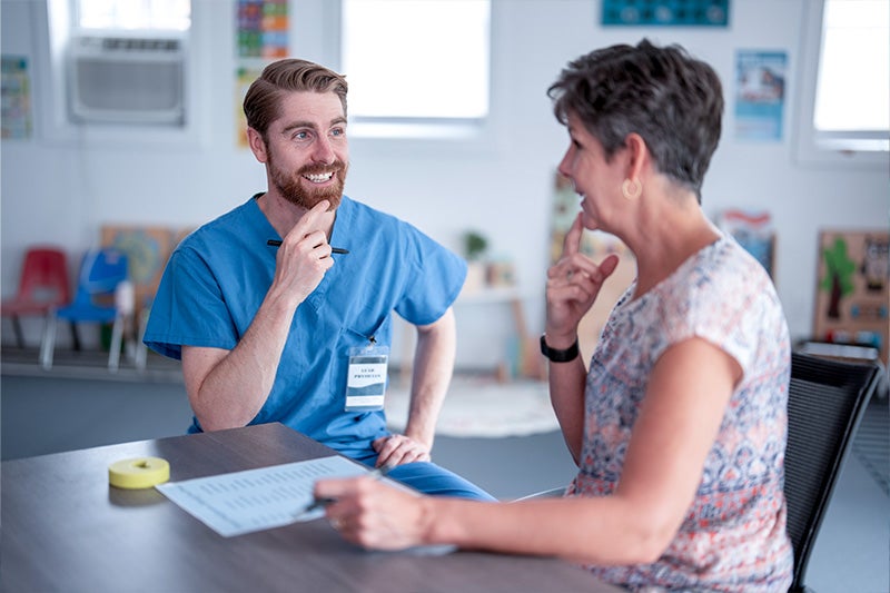 Speech-language pathologist working with an adult patient on swallowing therapy.