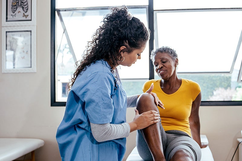 Patient with knee pain speaking with a Physical Therapist about pain management therapy options.