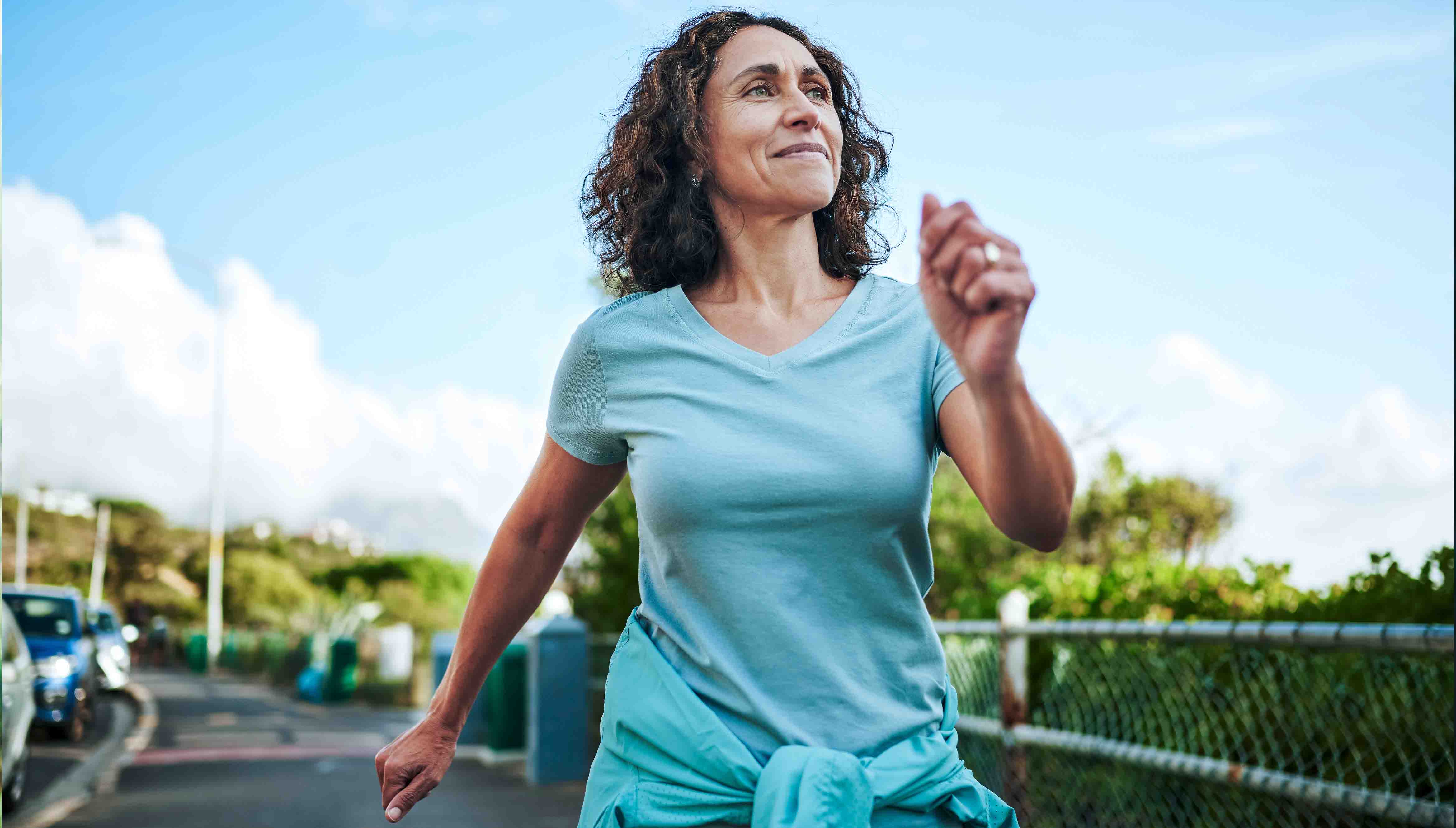 Woman with perimenopause power walking outside.