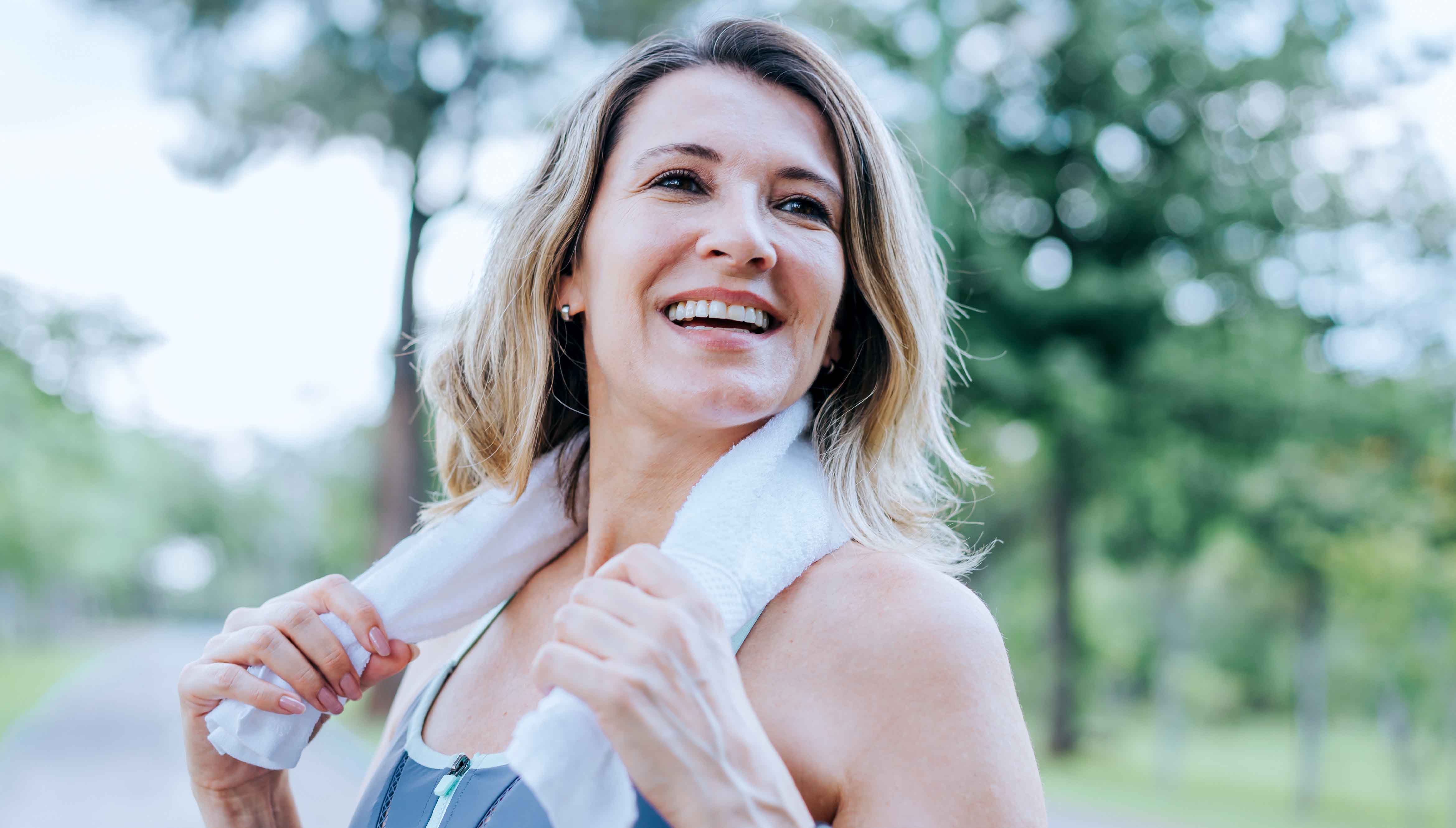 Woman who is of perimenopausal age with a towel around her neck after exercising.