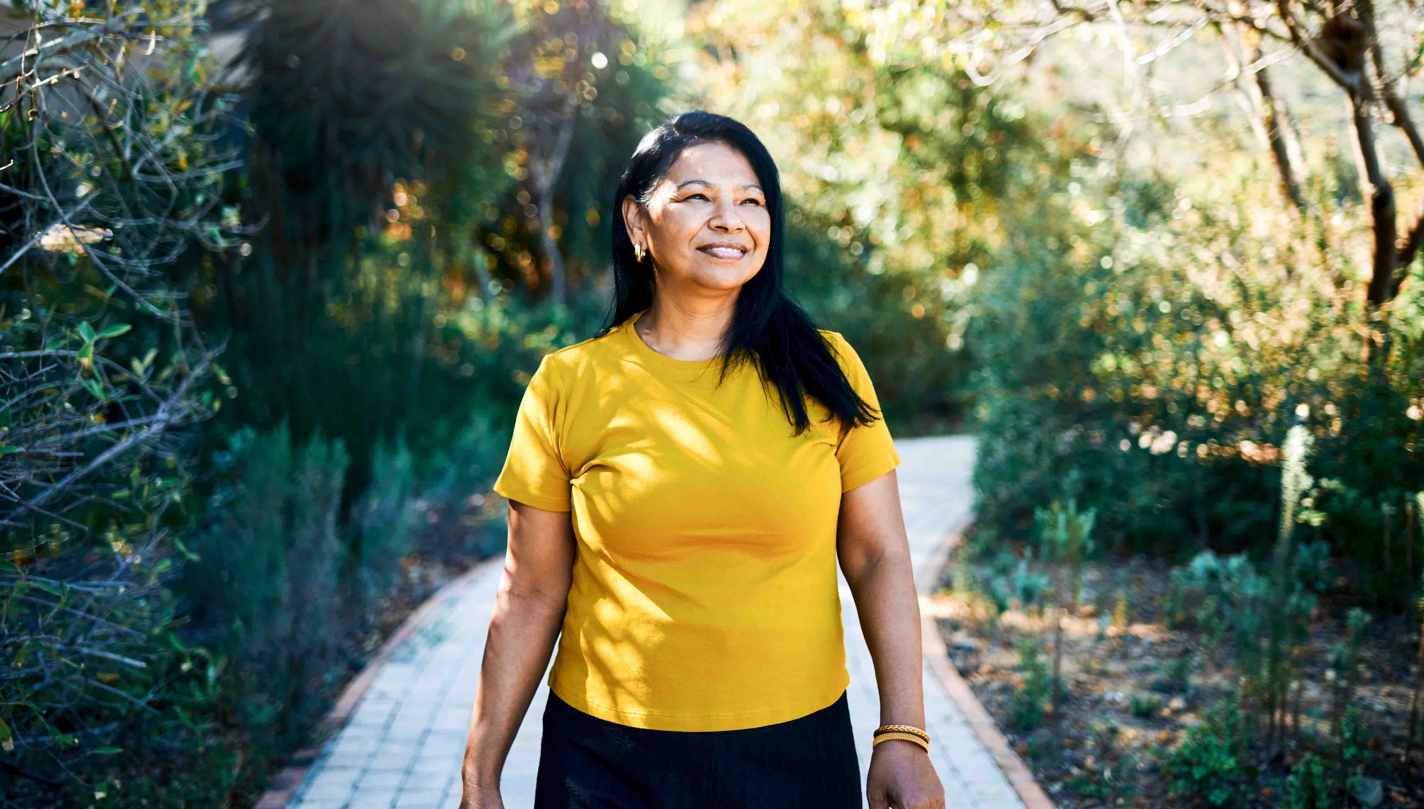 Perimenopausal woman smiling and taking a walk outside.