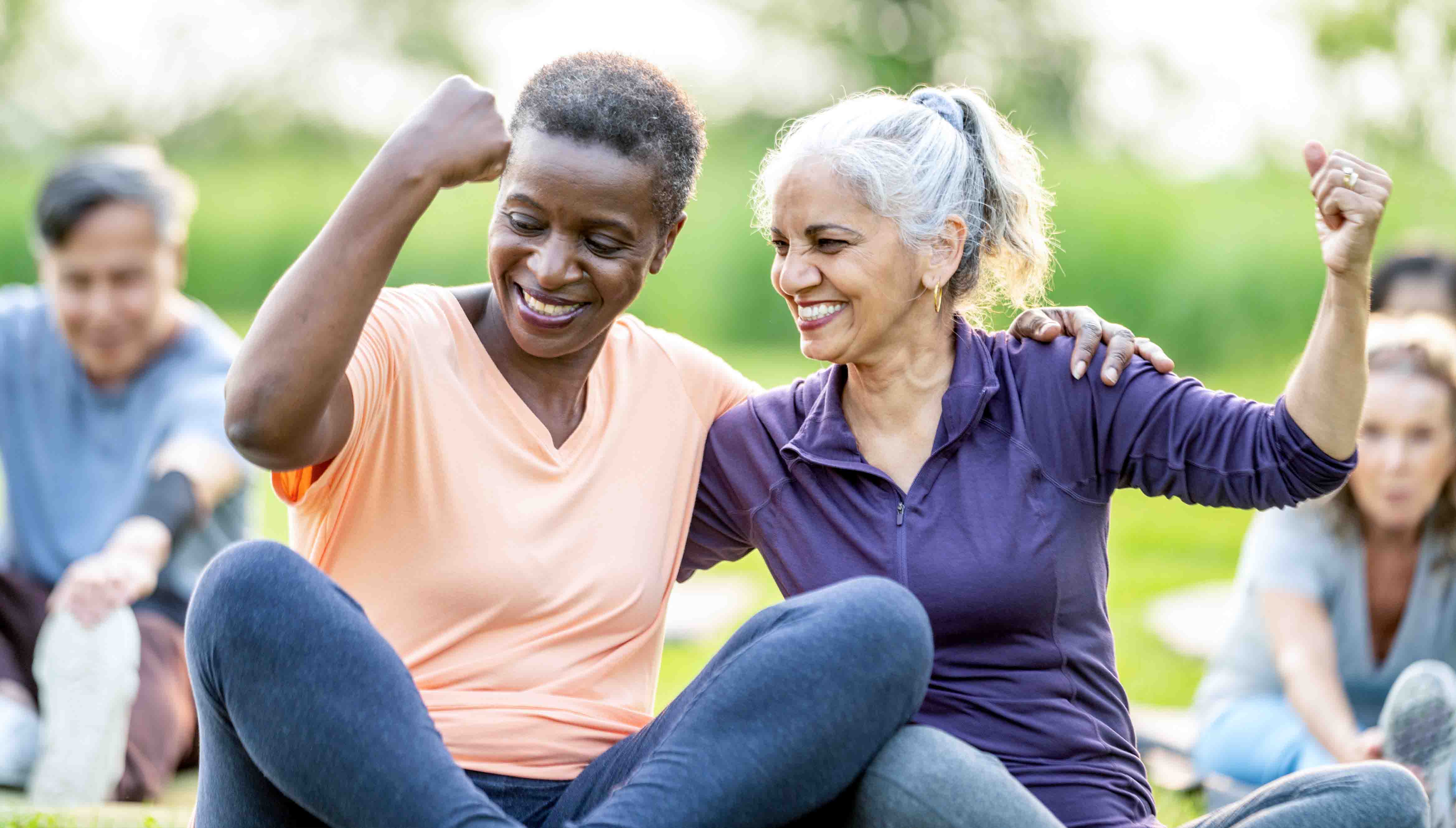 Two perimenopausal women showing off their muscles after a workout.