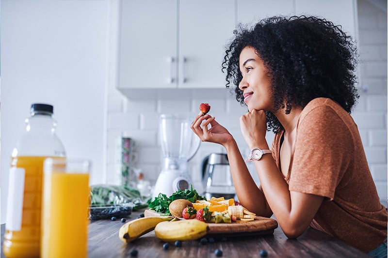 Happy woman eating breakfast at a table.