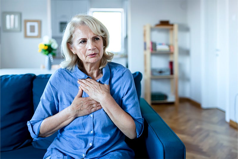 Woman with hands on her chest, possibly having a mild asthma attack.
