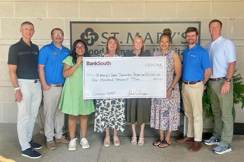 St. Mary staff pose with a large donation check outside the clinic.